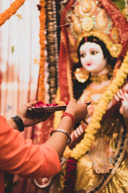 pexels-photo-9904376-9904376-1 A traditional Durga Puja ceremony with a devotee making offerings with flowers before a Durga idol.